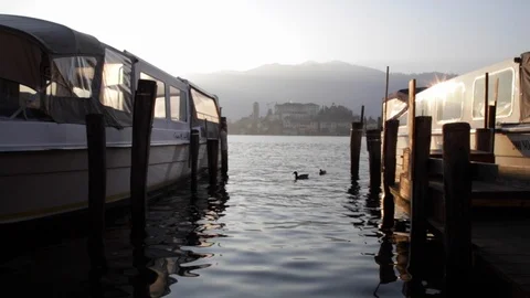 Lake Orta low angle between two moored boats, with ducks, slow motion Stock Footage 122280557
