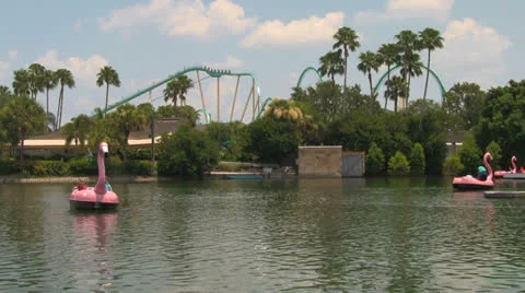 Lake with Paddle Boats and Rollercoaster in Background at Theme Park Stock Footage 23908835