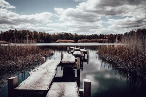 Lake with peer in a cloudy day with soft water and wooden texture and trees Stock-Fotos