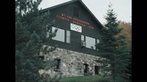 LAKE PLACID 1970s: An empty bobsled track surrounded by greenery and trees, with Stock Footage 299625945