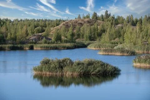 A lake with a plane surface and reflections against the blue sky and white. Stock Photos