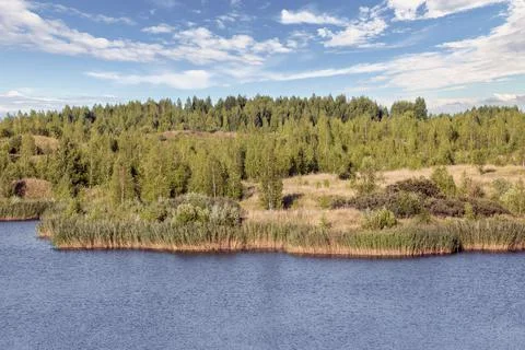 A lake with a plane surface and reflections against the blue sky and clouds. Stock Photos