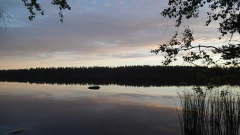 Lake with reflected evening sky and clouds against woods Stockbeeldmateriaal 101049835