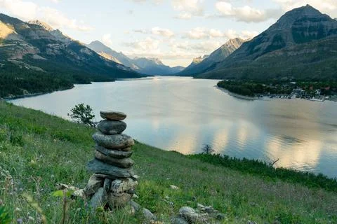 Lake reflections with a cairn of rocks in the foreground on a hillside Stock Photos