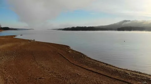 Lake With Rocky Dry Beach &amp; Leafless Trees w Misty Background 4K Drone 20sec Video stock 154145089