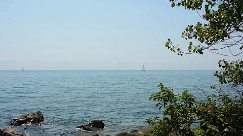 Lake sailboat rocks trees wind 02svv Stock Footage 46990045