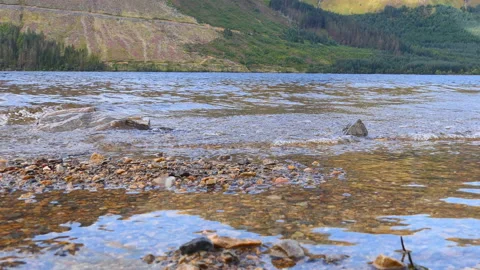 A lake shore with pebbles by a mountain. Stock Footage 112684309