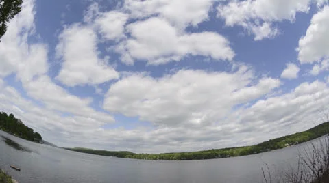Lake shore time lapse with clouds, ripples on water, shadows over trees Stock Footage 24692411