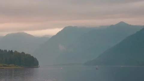 Lake shore at twilight. The sky is in the clouds, the mountains are in the Stock-Footage 277531422