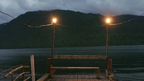 Lake shore at twilight. The sky is in the clouds, the mountains are in the 스톡 동영상 277531653