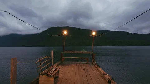 Lake shore at twilight. The sky is in the clouds, the mountains are in the Vídeo Stock 277532759