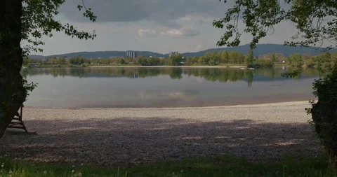 Lake shoreline with trees and distant buildings Stock Footage 332948640