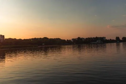 A lake with the sunset in the background, casting a warm glow Stock Photos