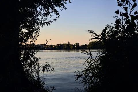 Lake at sunset framed by trees and seen from the shore Stock Photos