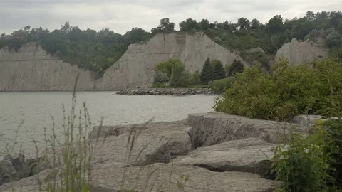 A lake surrounded by cliffs. Slider shot with rocks in the foreground. Stock Footage 77582788