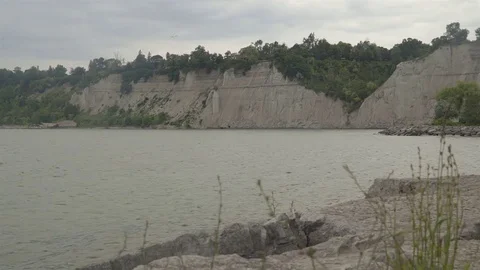 A lake surrounded by cliffs. Slider shot with rocks in the foreground. Video stock 77582875