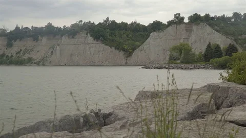 A lake surrounded by cliffs. Slider shot with rocks in the foreground. Stock Footage 77582929