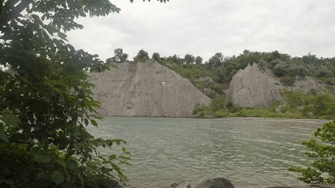 A lake surrounded by cliffs. Slider shot with rocks in the foreground. Stock Footage 77582997