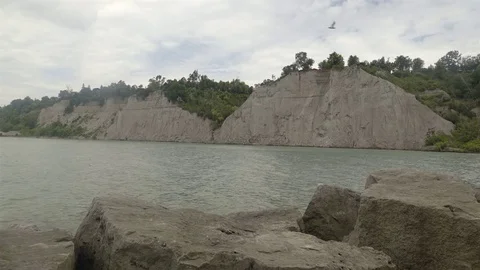 A lake surrounded by cliffs. Slider shot with rocks in the foreground. Stock Footage 77583272