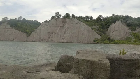 A lake surrounded by cliffs. Slider shot with rocks in the foreground. Stock Footage 77583351