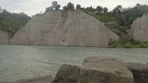A lake surrounded by cliffs. Slider shot with rocks in the foreground. Stock Footage 77583486