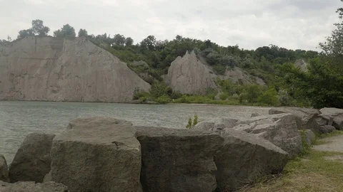 A lake surrounded by cliffs. Slider shot with rocks in the foreground. Stock Footage 77583610