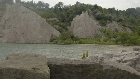 A lake surrounded by cliffs. Slider shot with rocks in the foreground. Stock Footage 77583802