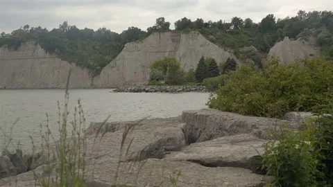 A lake surrounded by cliffs. Slider shot with rocks in the foreground. Stock Footage 77583878