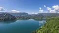 Lake surrounded by mountains, small island in middle, cloud reflection in water 4k or 4k+ Resolution