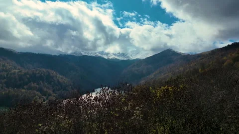 A lake surrounded by snow-capped mountains, green hills and thick clouds Stock Footage 310662653