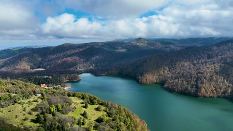 A lake surrounded by snow-capped mountains, green hills and thick clouds Stock Footage 310662775