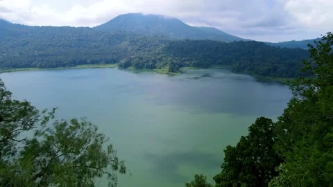 Lake view with mountain, cloudy sky, and green forest, shot from aerial Stock Footage 219469605