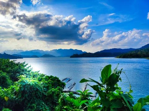Lake view with mountains and clouds during daytime near green foliage. Chia.. Stock Photos