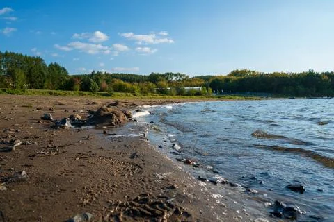Lake with waves on the background of a sandy beach and forest Stock Photos