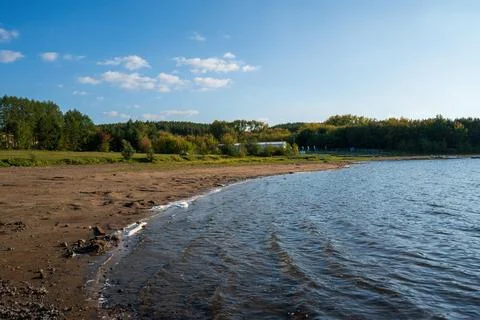 Lake with waves on the background of a sandy beach and forest Stock Photos