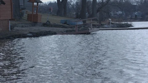 Lake with waves, dock and tipped over boat. Squirrel running in slow motion. Stock Footage 88684429