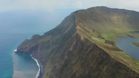 Lakes and fields of Caldeirao volcano. Green slopes and rocky cliff at cloudy Stock Footage 119601039