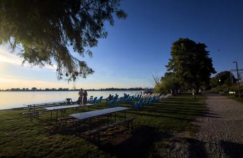 Lakeshore with deck chairs at sunset Stock Photos