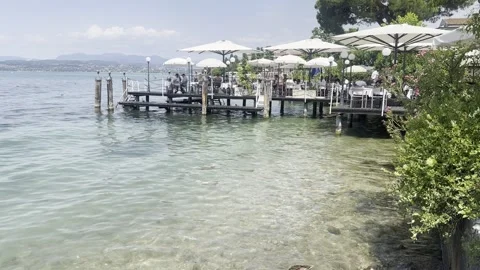 Lakeside café and pier panorama — Lake Garda Italy lifestyle clip. Stock Footage 320503545