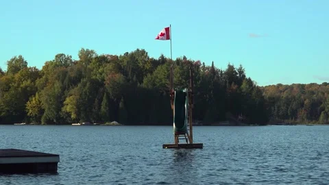 A lakeside features a floating waterslide with a Canadian flag Stock Footage 325790160