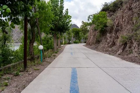 Lakeside road between trees and rocky hillside Fotos Stock