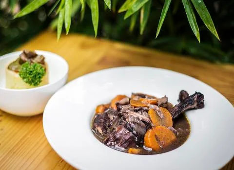 Lamb and carrot red wine casserole stew on wooden table Stock Photos