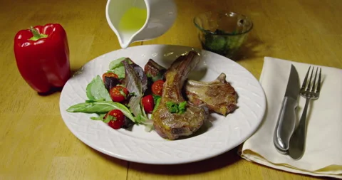 Lamb Chops And Olive Oil Being Poured Over Salad Stock Footage 243449502