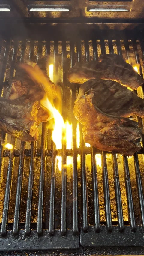 Lamb chops on barbecue grid sizzling over flames Stock-Footage 332545600