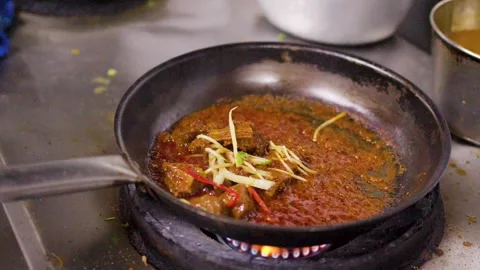 Lamb Curry Simmering in Pan and Garnished with Ginger and Herbs Stock Footage 346579927
