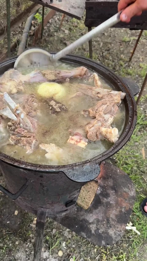 Lamb meat is cooked in a cauldron over a campfire Stock Footage 276258020