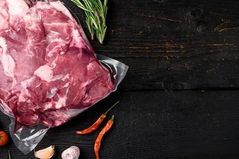 Lamb meat raw pack, with ingredients and herbs, on black wooden table backgro Stock Photos
