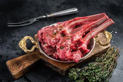 Lamb mutton chop steak, raw meat cutlet in a skillet with herbs. Black Foto stock