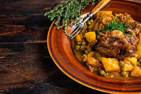 Lamb oxtails ragout with vegetables in a rustic plate. Dark wooden background Stock Photos