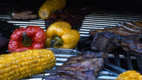Lamb Ribs and Vegetables on a Rotating Grill, meat and corn on a barbecue, slow Stock Footage 89333131